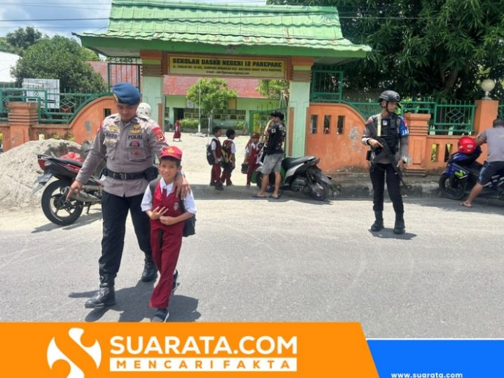 Personel Brimob Batalyon B Pelopor Satuan Brimob Polda Sulsel Bantu Anak Sekolah Menyebrangi Jalan Padat Kendaraan