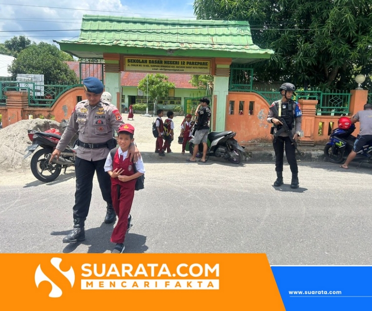 Personel Brimob Batalyon B Pelopor Satuan Brimob Polda Sulsel Bantu Anak Sekolah Menyebrangi Jalan Padat Kendaraan